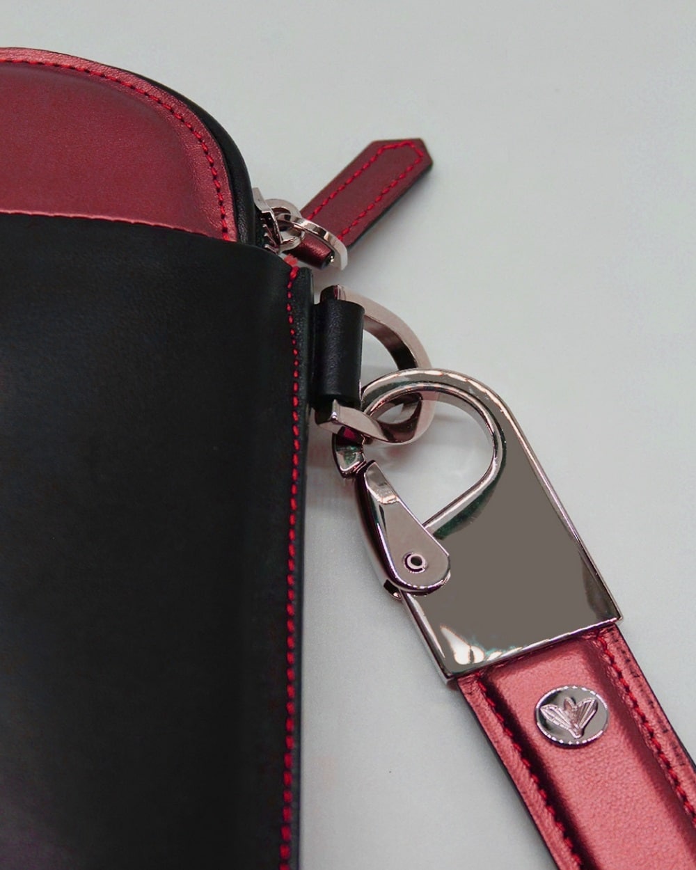 Pouch / Clutch in iridescent red leather with central padded iconic Dea-Cult Sphinx motif. Detail.