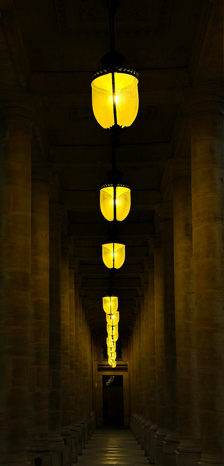 Galerie parisienne &agrave; colonnades &eacute;clair&eacute;e par des lanternes &agrave; la tomb&eacute;e de la nuit